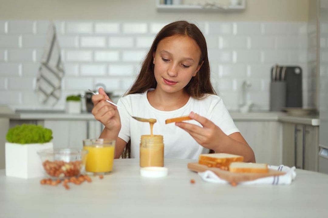 Une petite fille qui mange du beurre de cacahuète