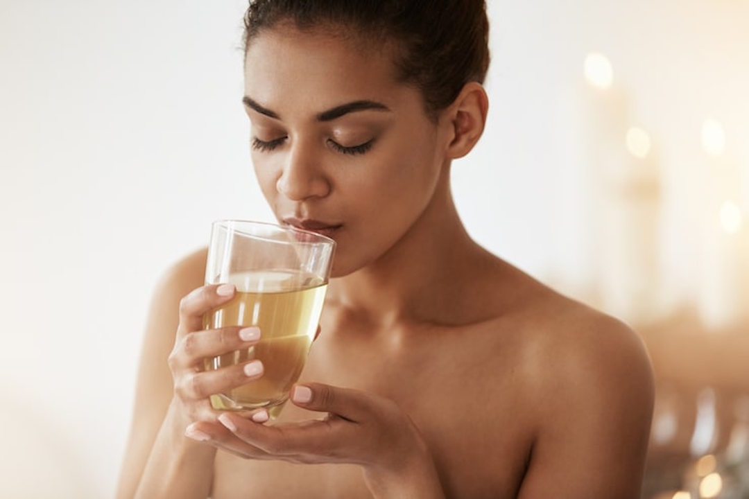 Une femme qui boit un verre de Sève de bouleau