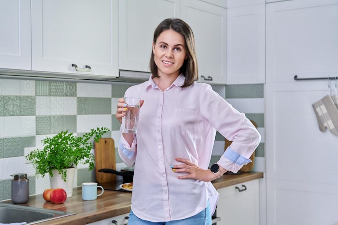 Une femme qui se tient le ventre avec le sourire, gr&acirc;ce &agrave; une bonne digestion et la bicarbonate de soude