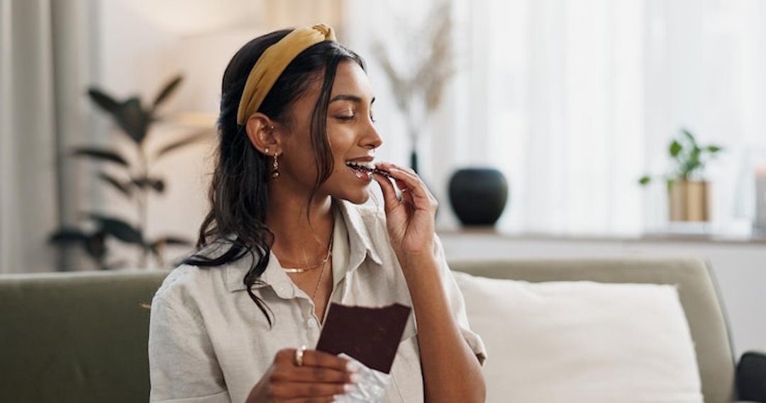Une femme qui mange du chocolat pour le magnésium
