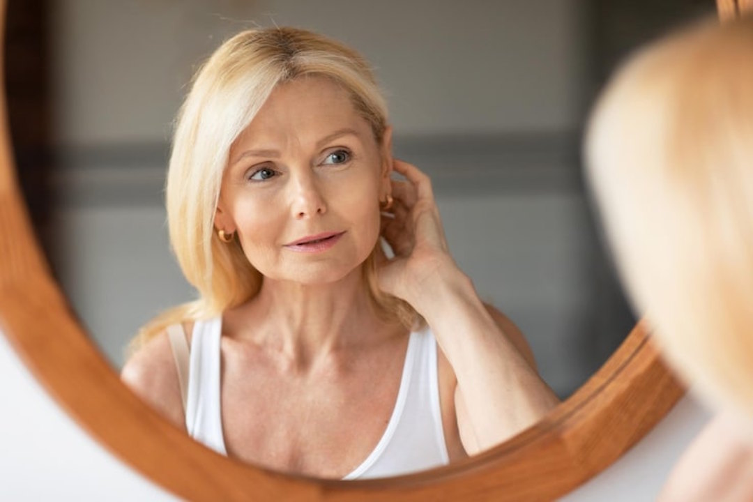 Une femme qui regarde le vieillissement de sa peau dans un miroir