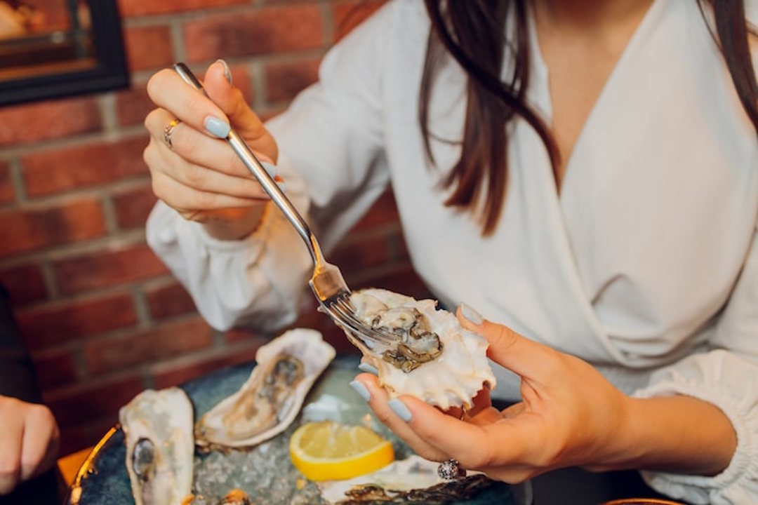 Une femme qui mange des fruits de mer pour le collagène marin