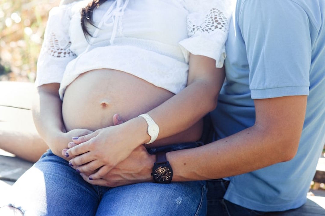 Une femme enceinte et son mari qui tient son ventre