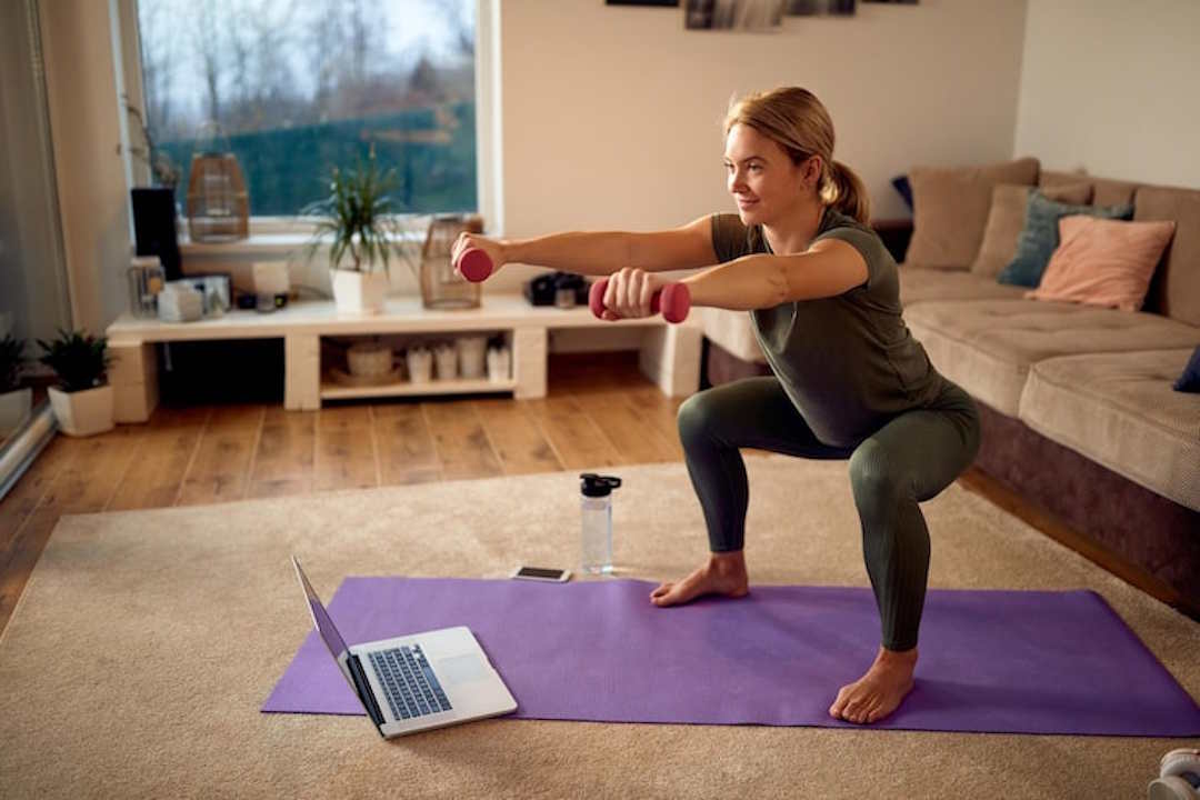 Une femme qui fait une séance intense sur un home-trainer chez elle.