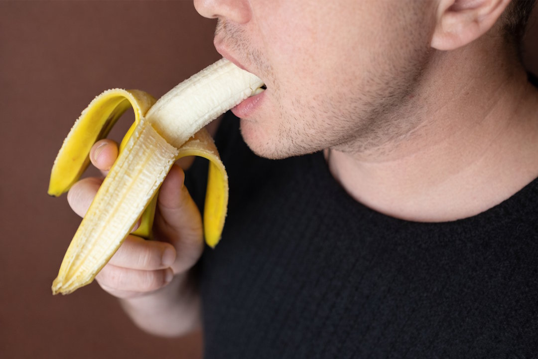 Un homme européen qui mange une banane