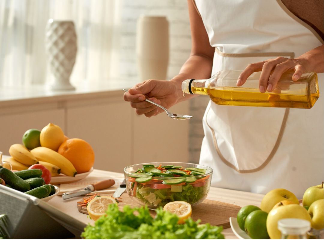 Une personne qui verse de l'huile dans une salade