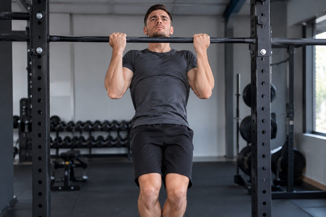 Un homme qui fait la traction en supination (Chin-Up)