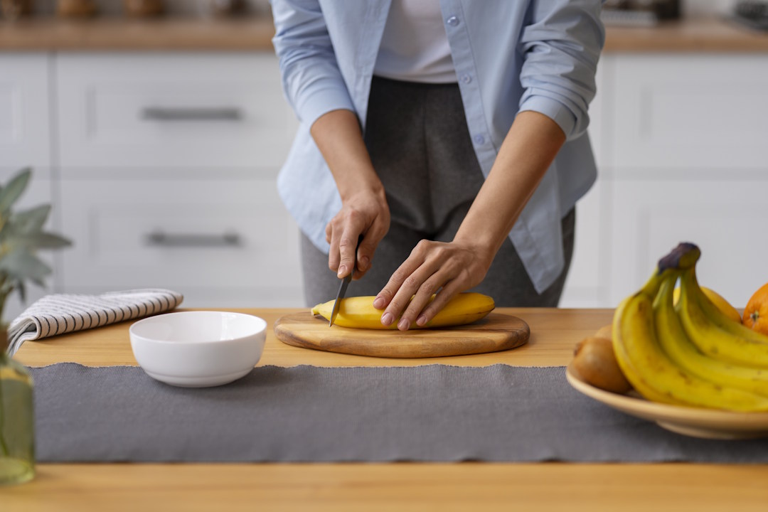 Une femme qui coupe de la banane dans sa cuisine