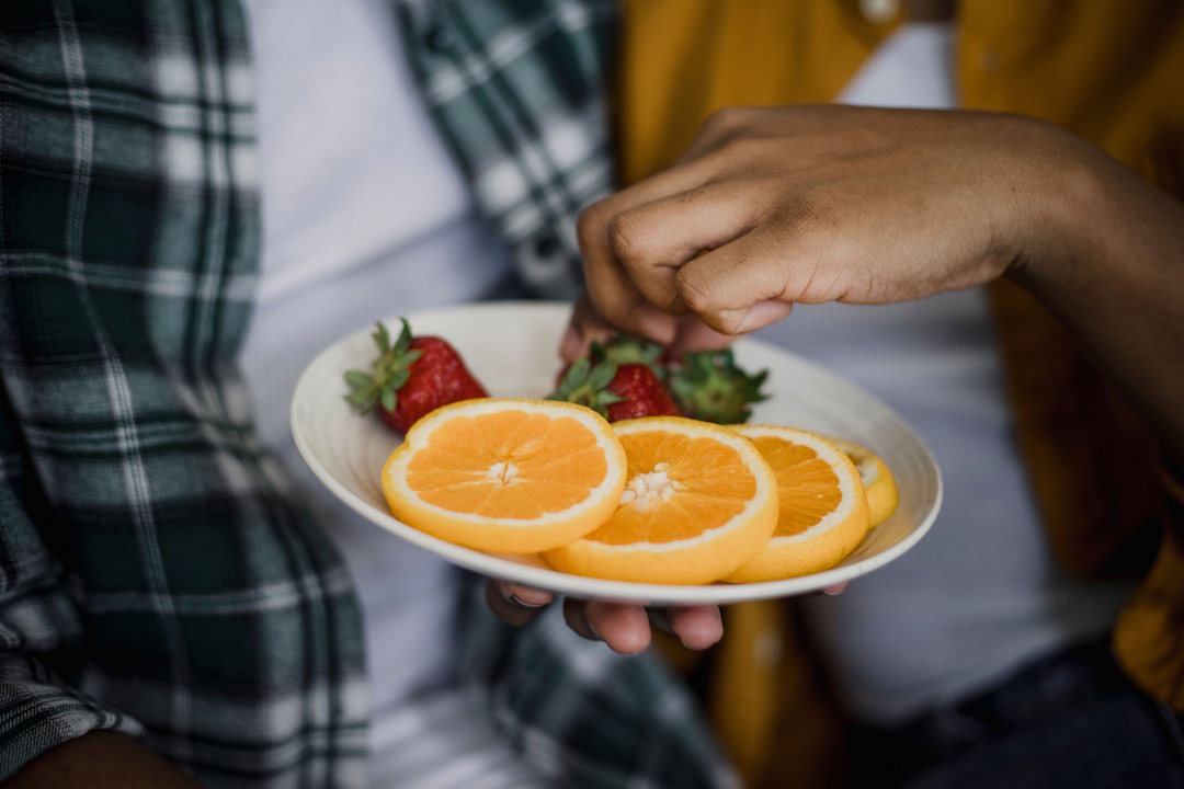 Une personne qui mange une orange découpée en rondelle