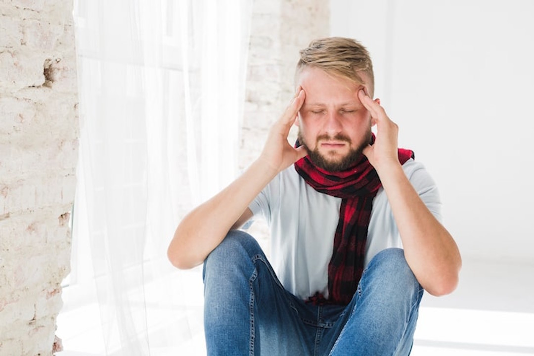 Un homme qui a mal à la tête à cause d'une grippe