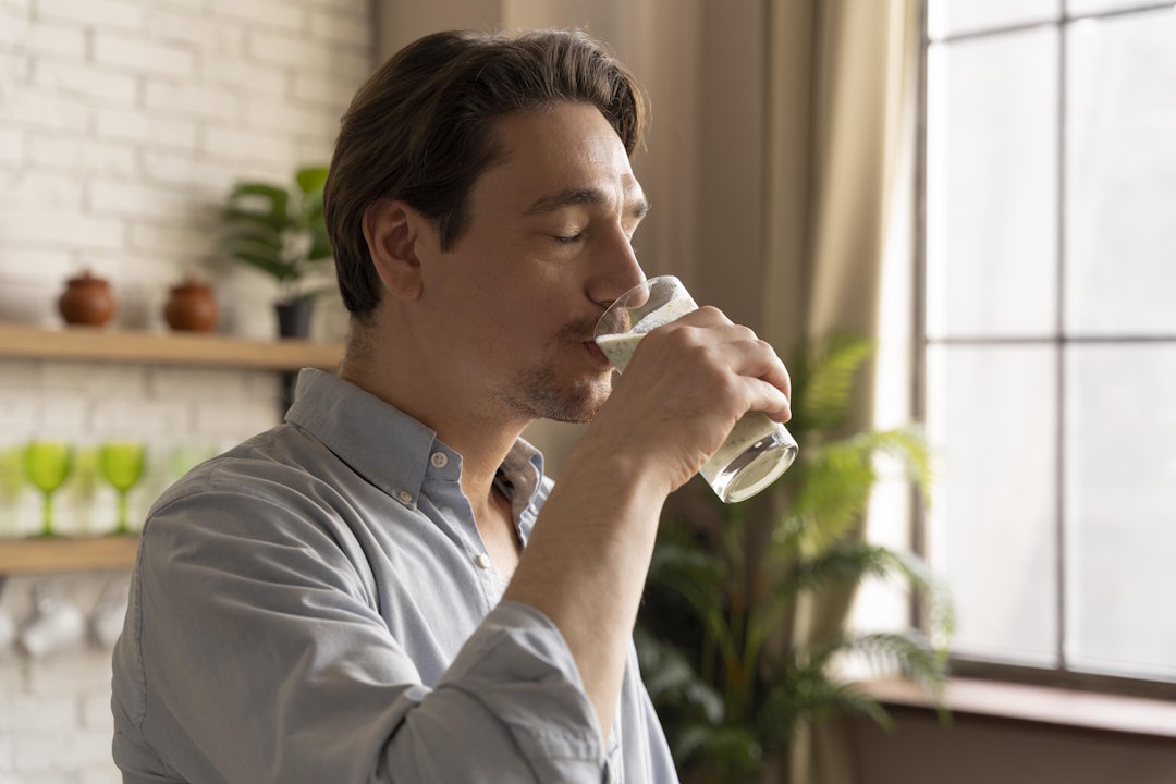Un homme qui boit une boisson fraiche pour soulager son mal de gorge
