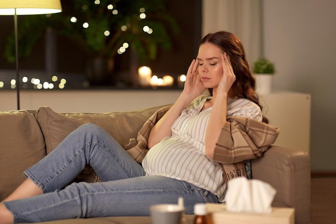 Une femme enciente qui souffre de migraine sur son canapé