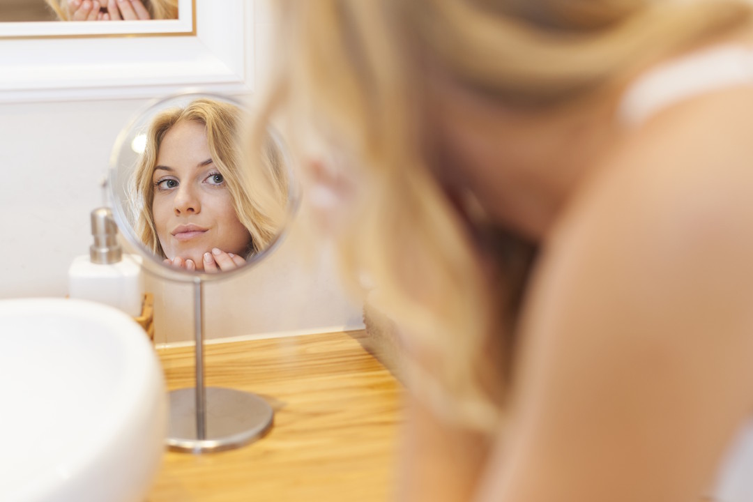 Une femme qui regarde sa peau et les bienfaits du MSM sur la peau