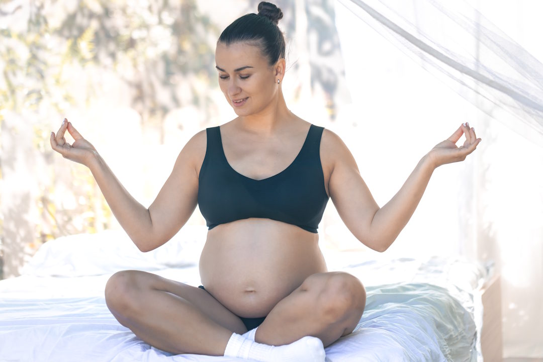 Une femme occidentale enceinte qui fait du yoga