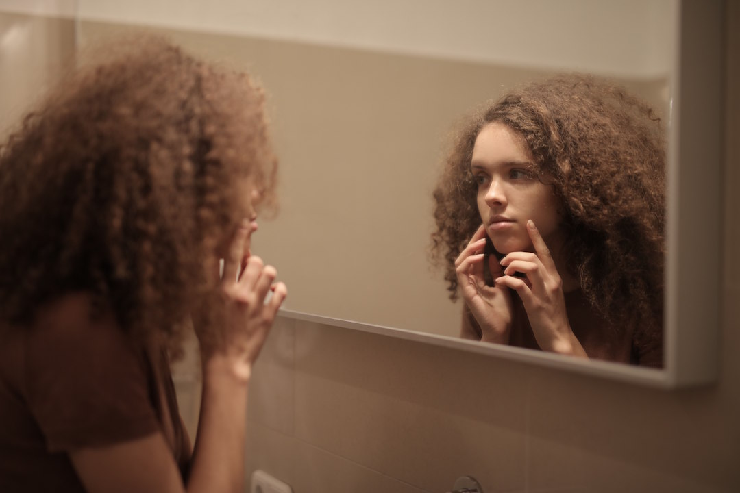 Une femme qui regarde des signes d'herpès dans le miroir