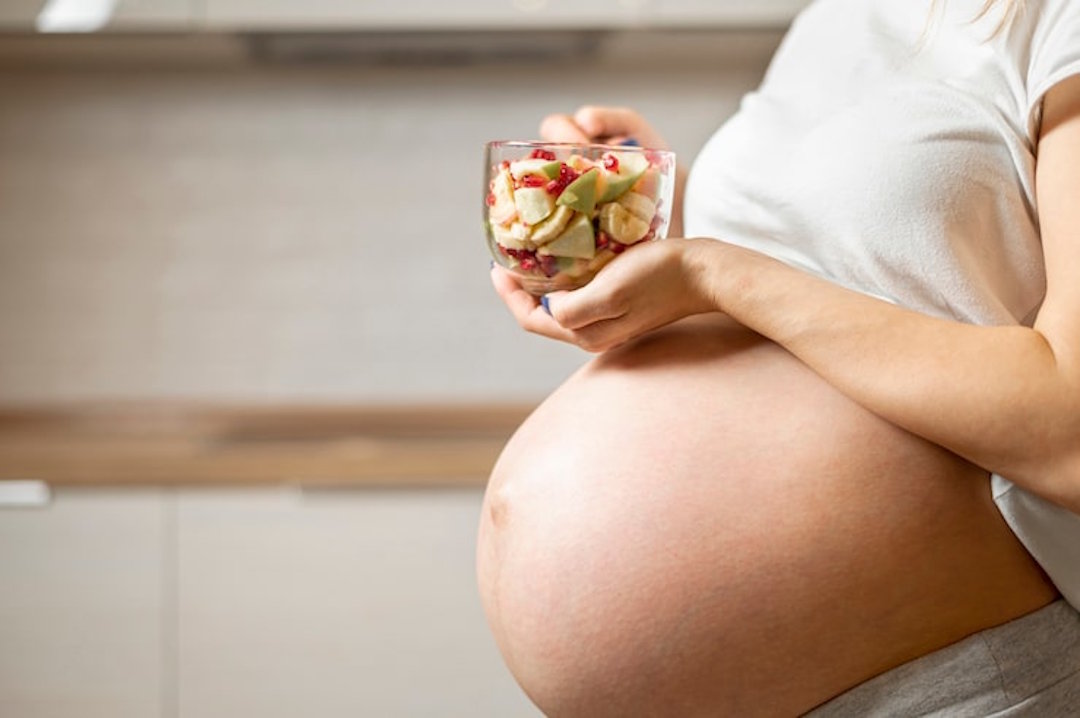 Une femme enceinte avec un bol de fruits