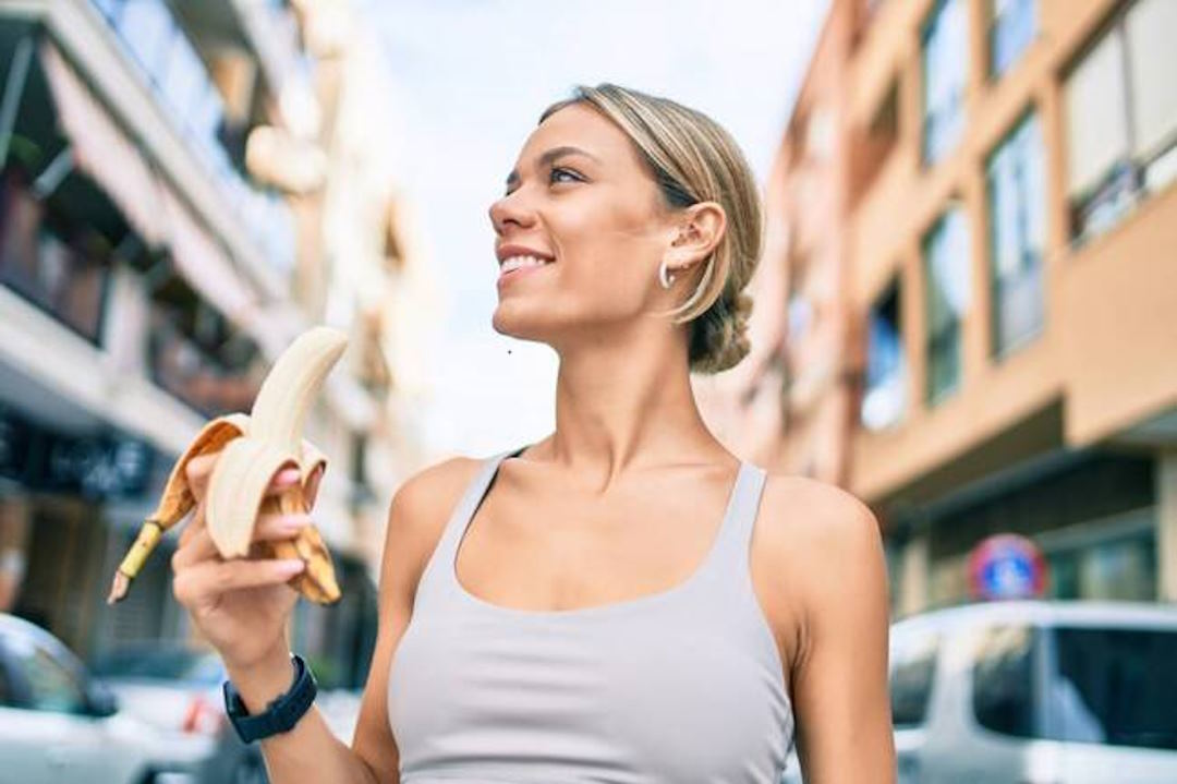 Une femme en tenue de sport qui tient une banane dans la main