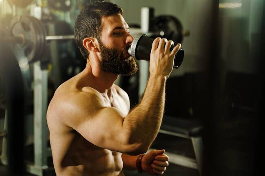 Un homme qui boit son protéine en plein exercice physique