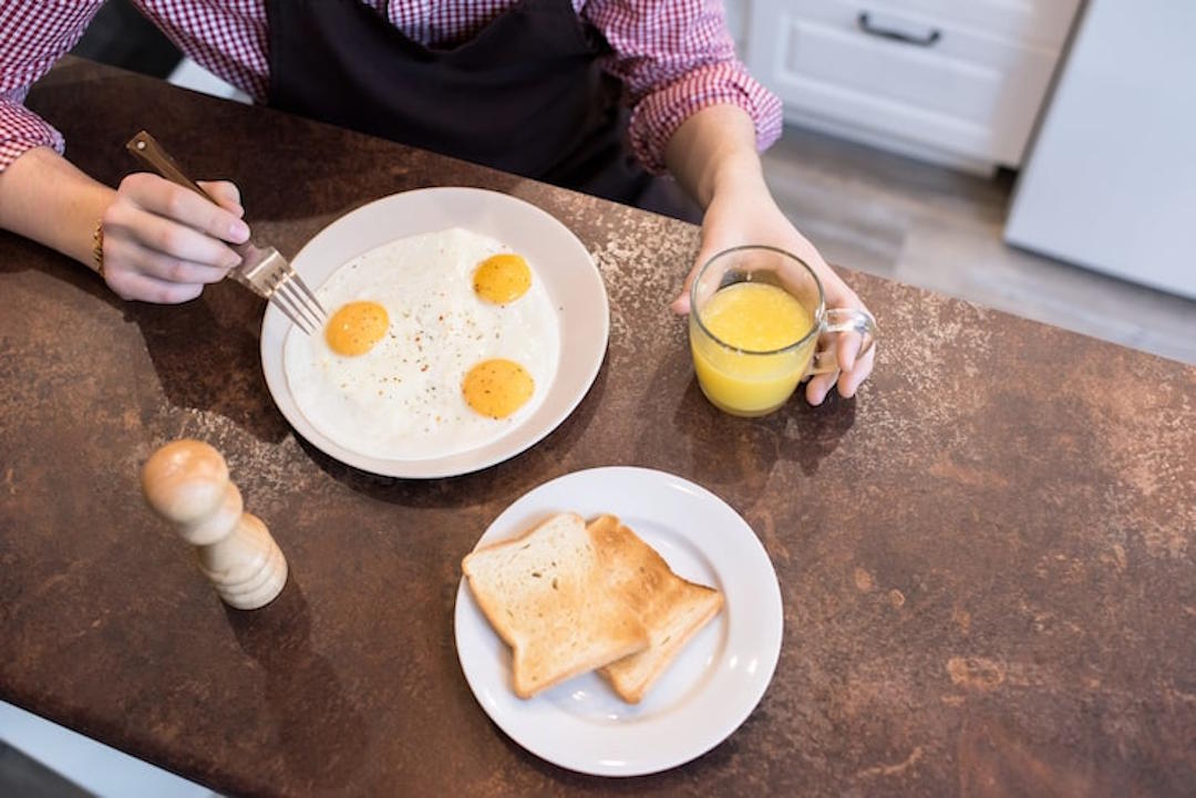 Une personne européenne qui lange des œufs au petit déjeuner