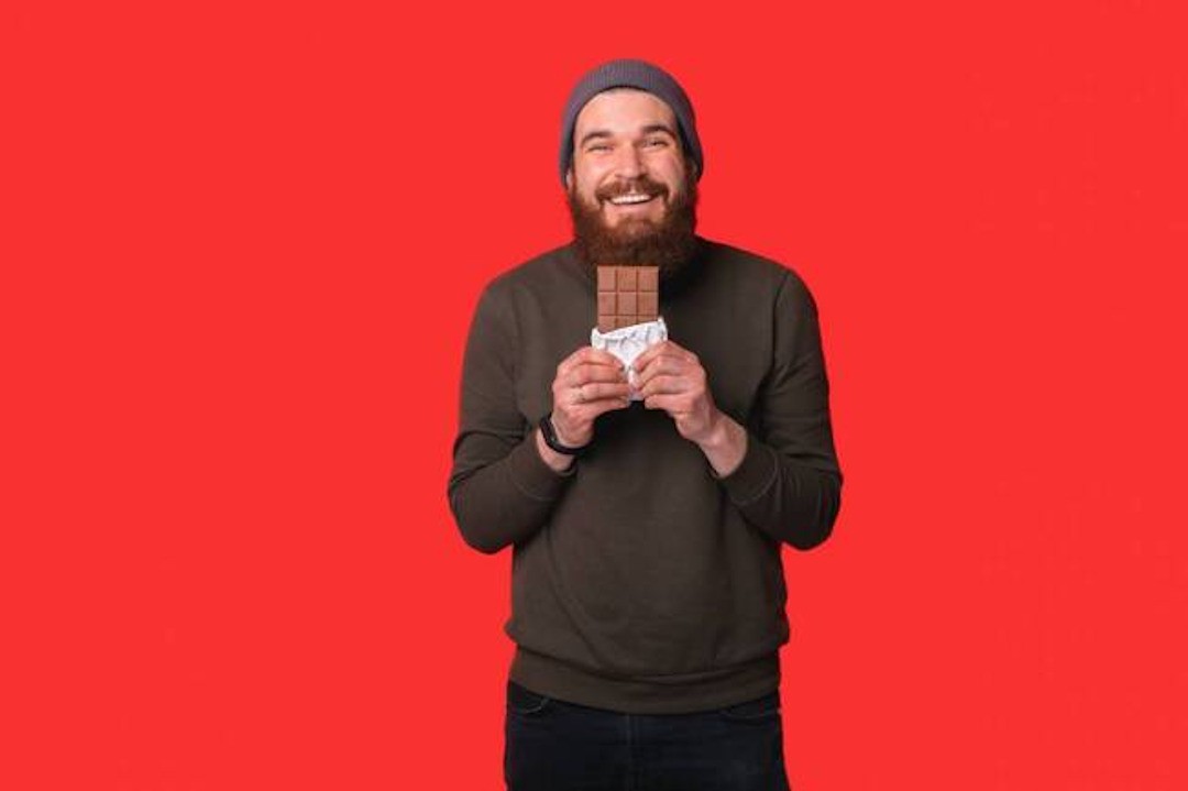 Un homme qui tient une tablette de chocolat noir