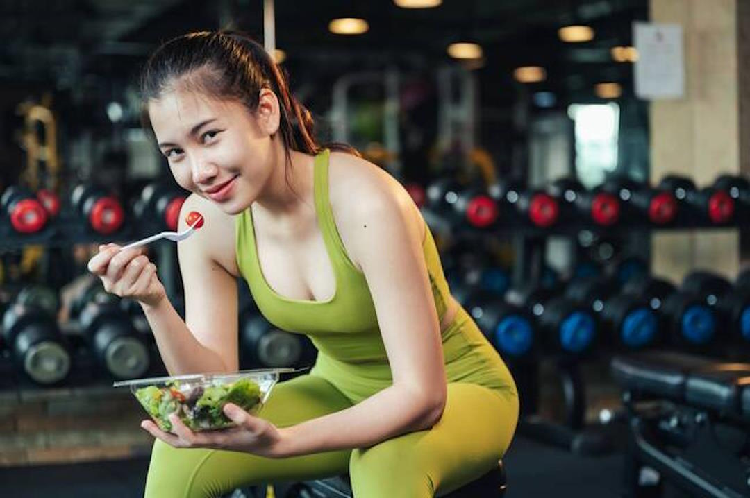 Une femme qui prend un aliment bien équilibré dans une salle de sport