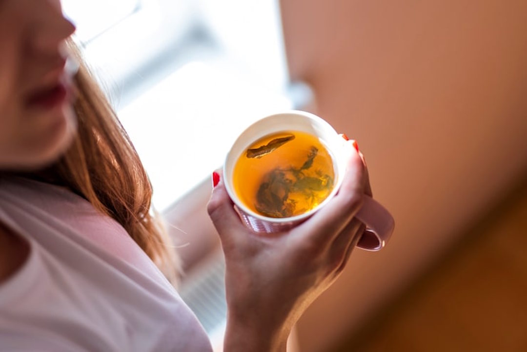 Une femme qui boit une infusion de curcuma