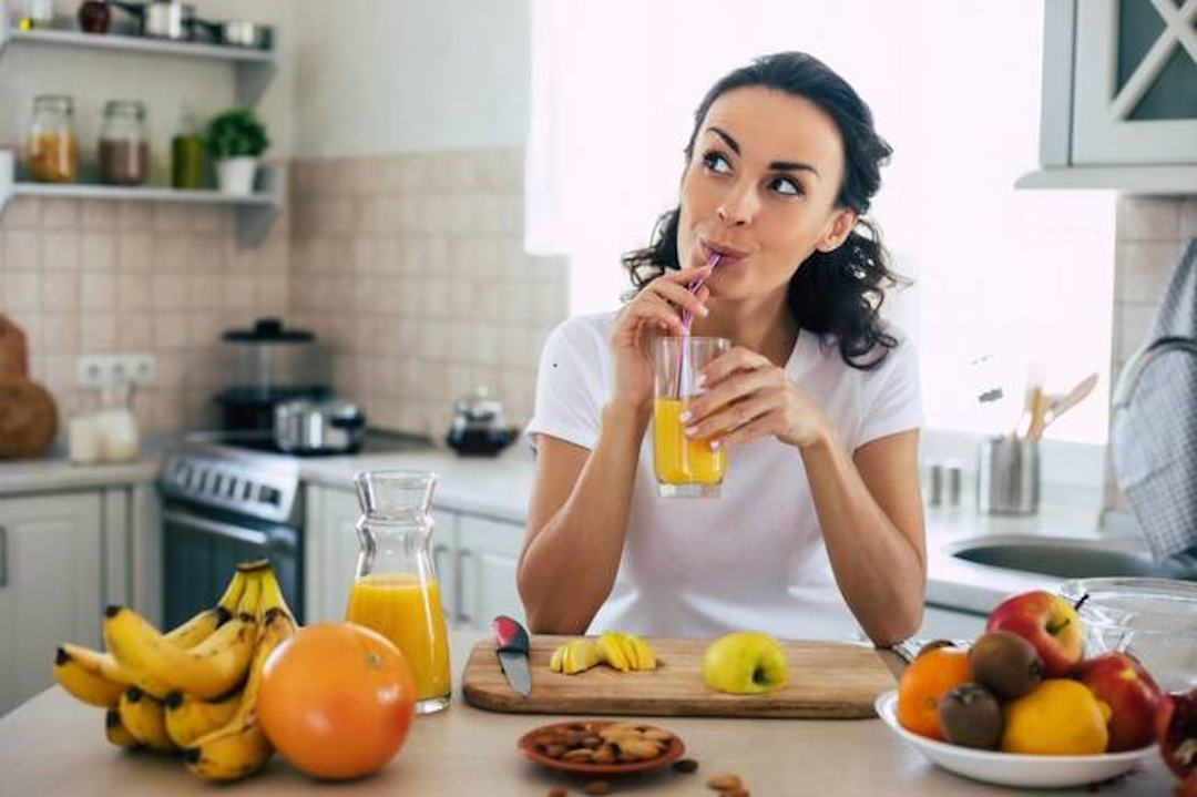Une femme qui boit du jus de fruits riche en vitamine D