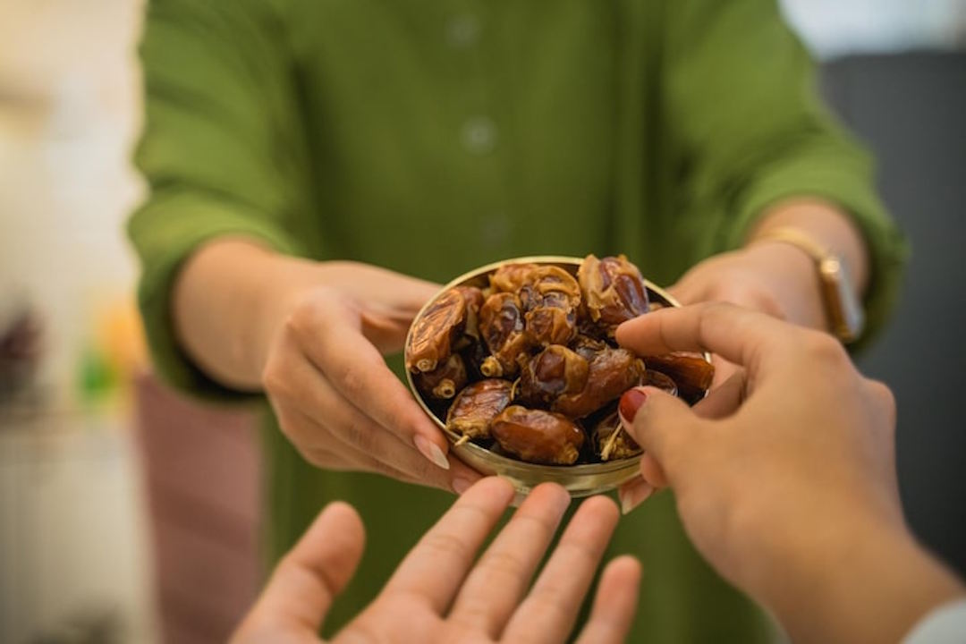 Une personne qui offre des dattes à une autre pour les bienfaits