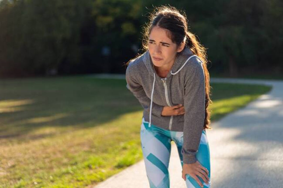 Une femme qui souffre de douleur en bas du ventre pendant une course à pieds