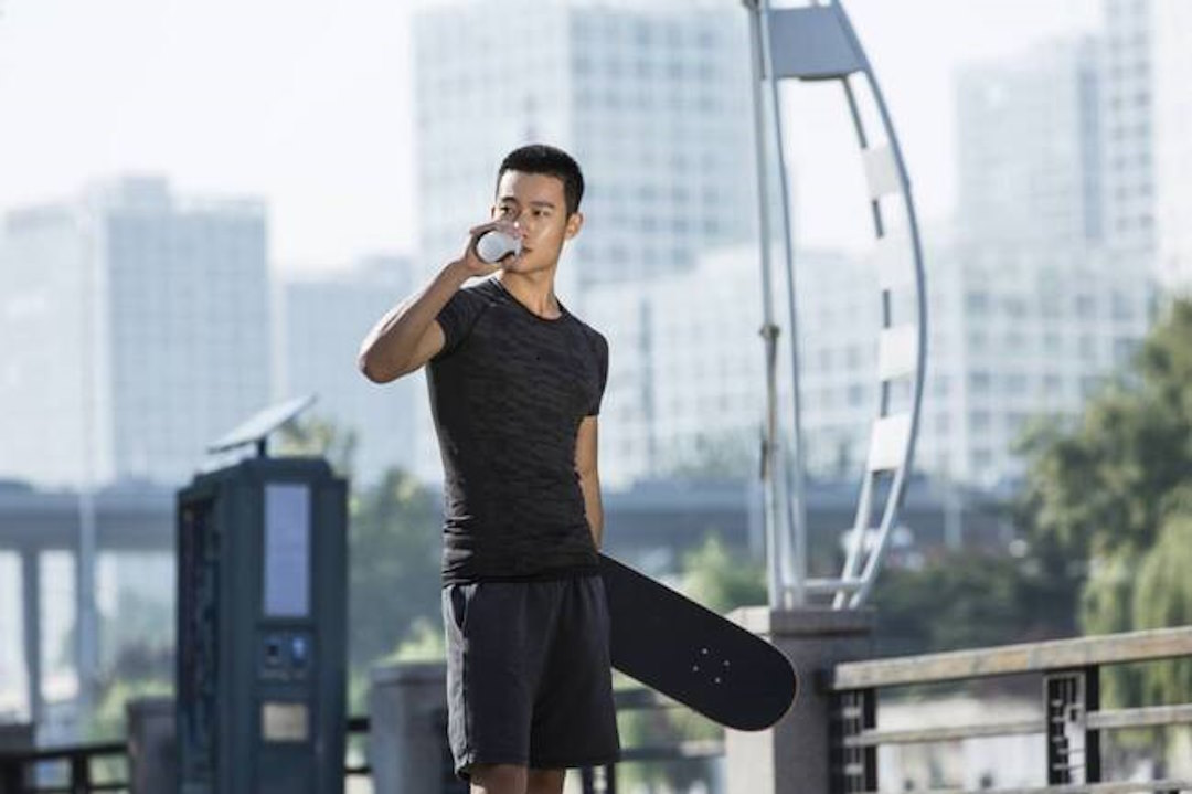 Un homme qui fait du skate et boit de l'eau