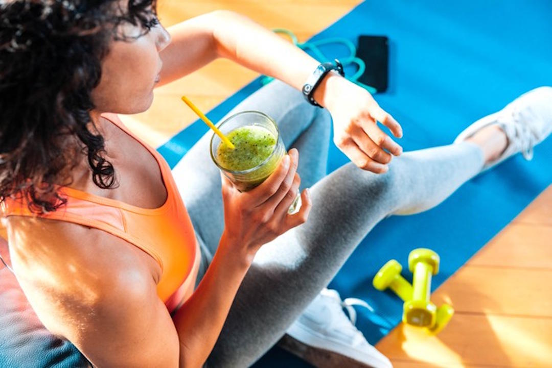 Une femme qui prend une solution avec de la whey isolate après le sport