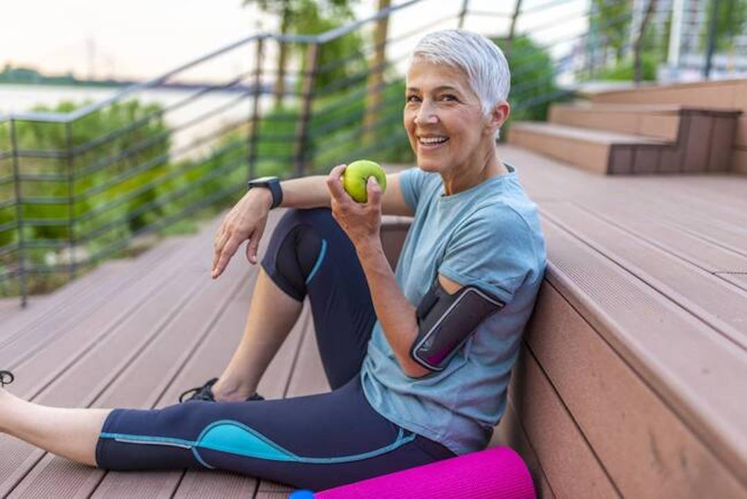 Une femme assise après le sport qui mange une pomme