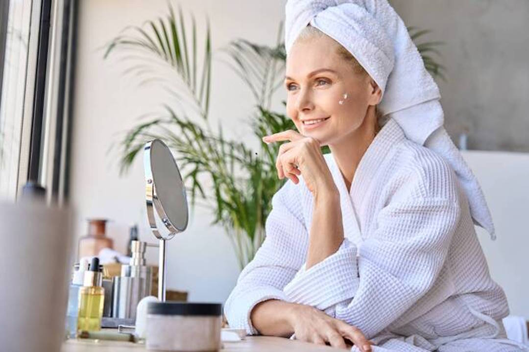 Une femme qui prend bien soin d'elle en mettant de la crème au visage