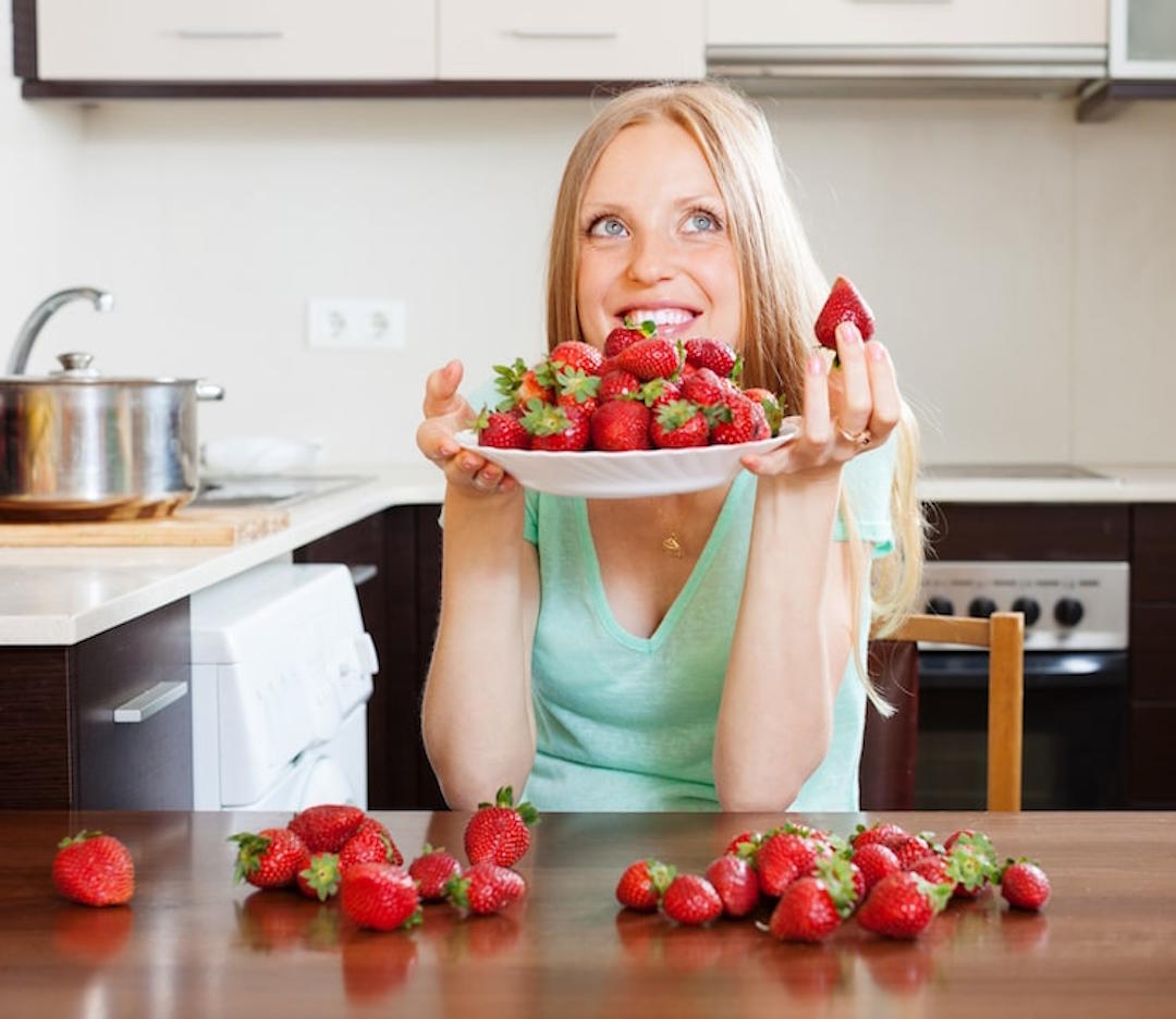 Une jeune femme qui mange des fraises