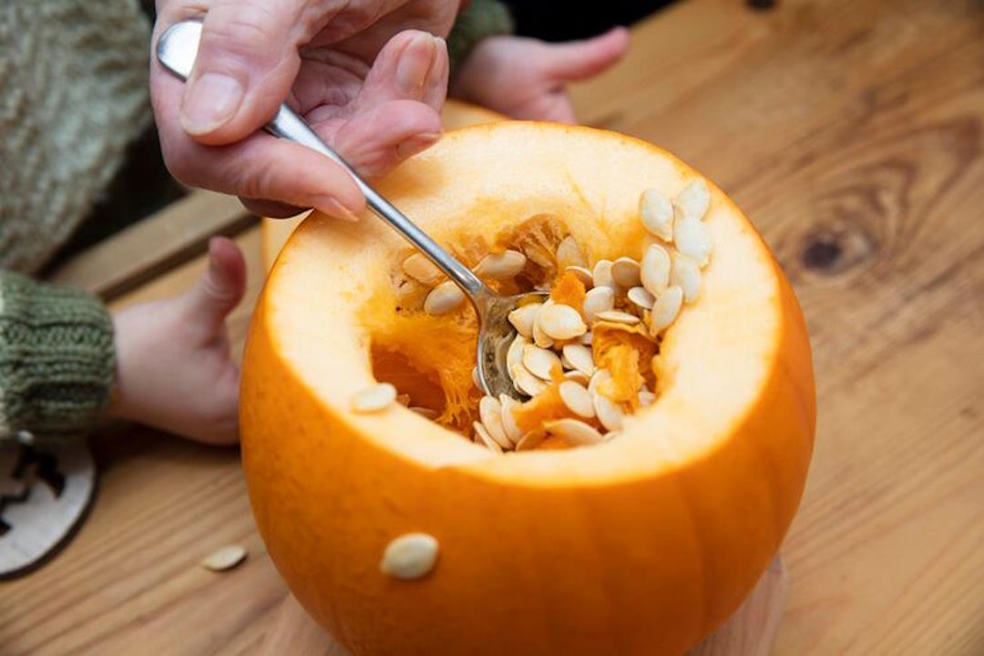 Une personne qui prend des graines de courge avec une cuillière