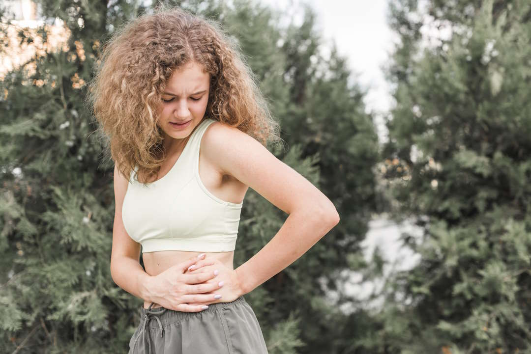 Une femme qui se tient le côté gauche de son ventre