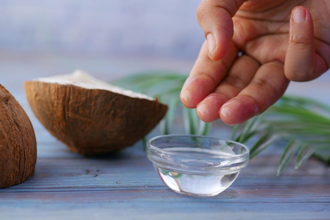 Une personne qui prend de l'huile de coco avec les doigts