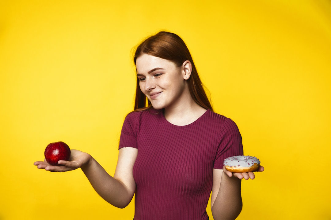 Une femme qui tient un donut et une pomme