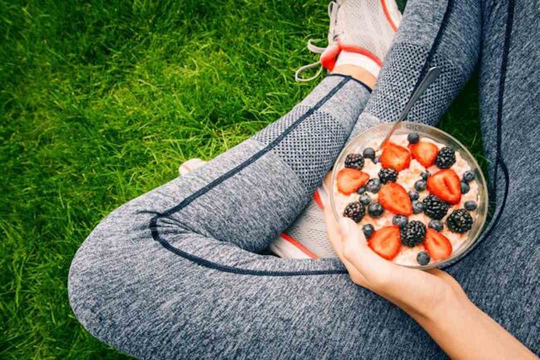 Une personne qui tient un bol rempli de fruits rouges 