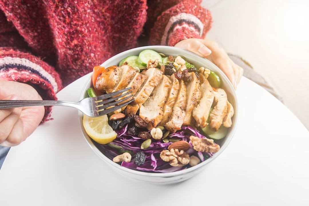 Une personne qui mange une assiette avec des aliments riches en protéines