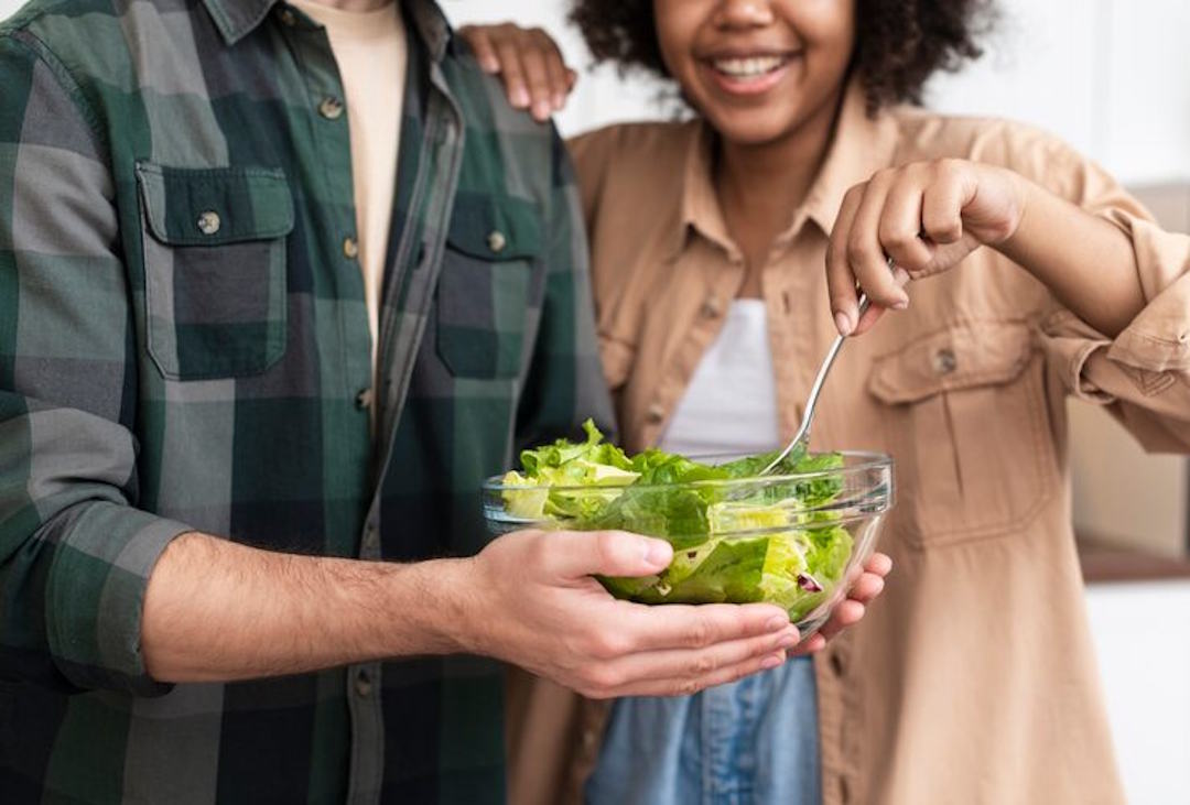 Un homme et une femme mange de la salade verte
