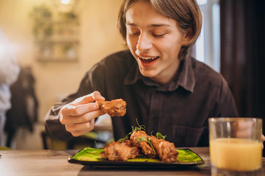 Un homme qui mange du poulet cuit pour un bon apport en vitamine B3