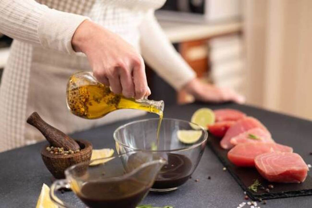 Une femme qui verse de l'huile en oméga 3 dans une sauce