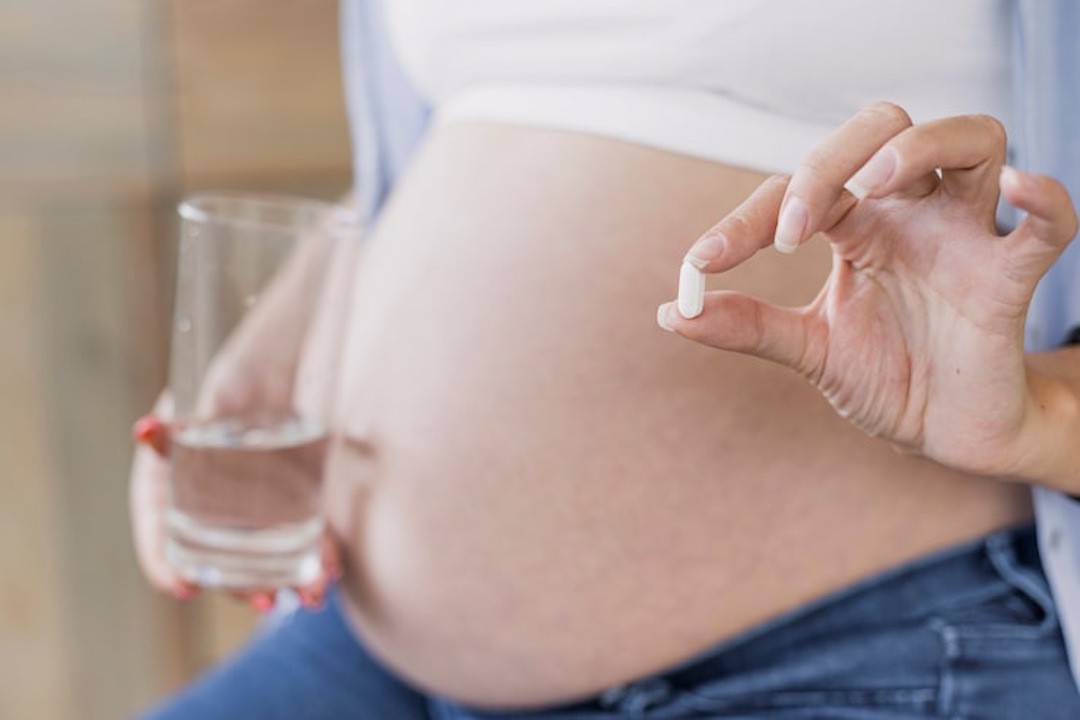 Une femme enceinte qui prend son complément de multivitamines