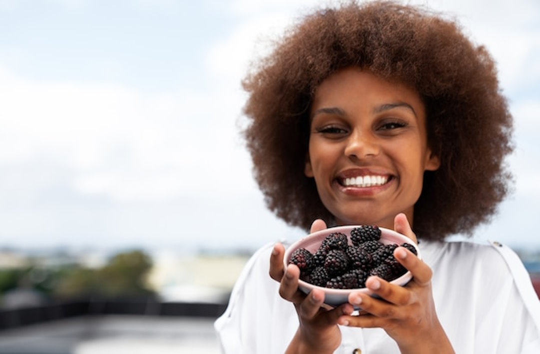 Une femme qui tient des fruits rouges dans sa main