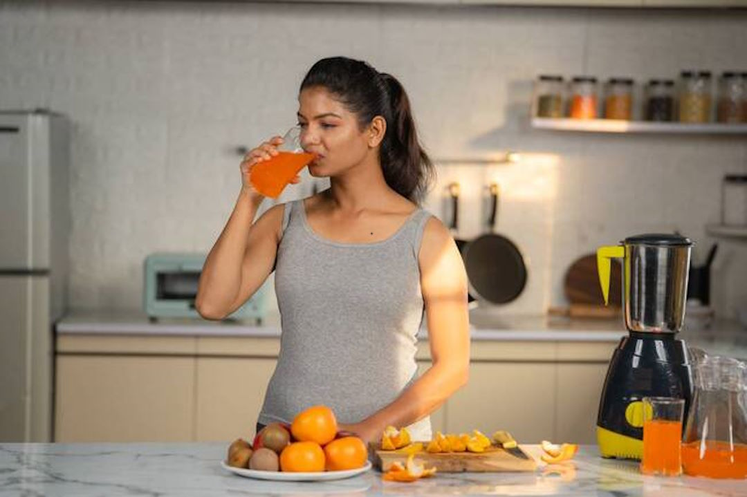 Une femme qui boit du jus d'orange