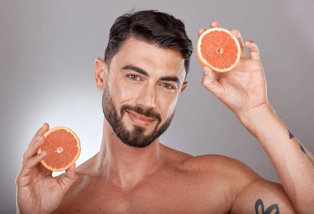Un homme qui tient deux moitiés d'orange dans deux mains