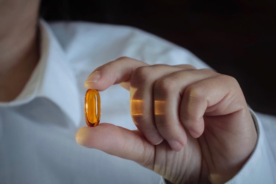 Un homme qui montre un gélule de Vitamine D3