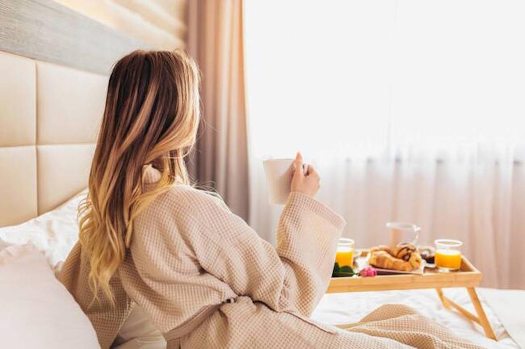 Une femme qui prend un petit déjeuner et de la vitamine D au lit