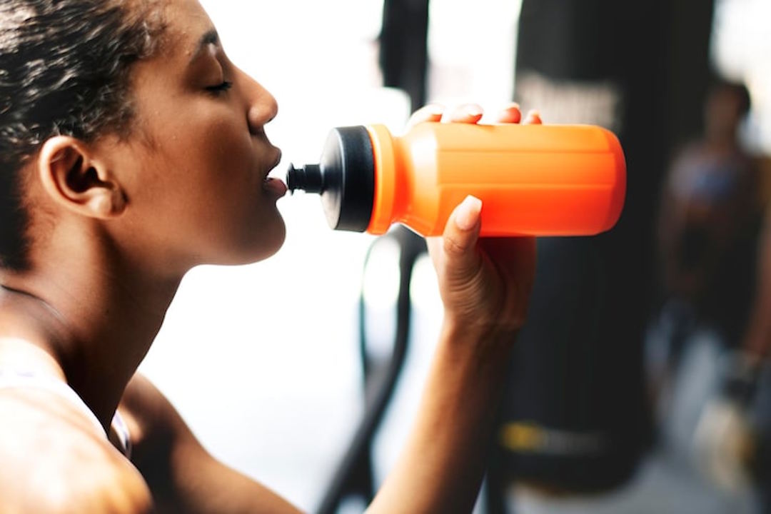 Une femme qui boit de l'eau en Pre workout